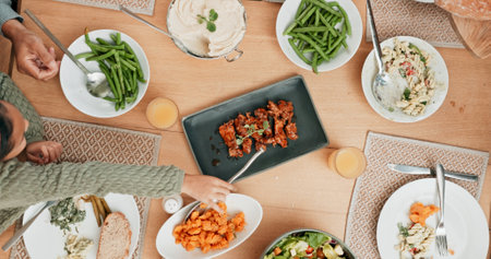 Food, meal and table with people at dining room of home from above for celebration or festive holiday. Cooking, roast or supper with family eating in apartment together for event or social gatheringの写真素材