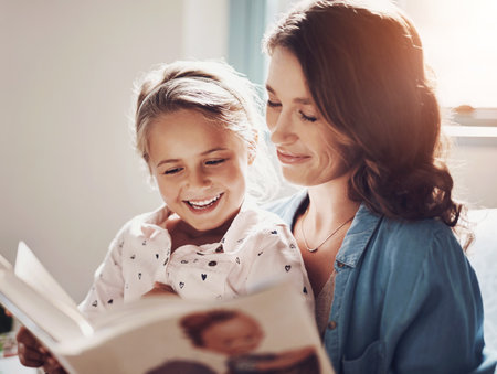 Mother, girl and excited with storytelling in home for fairytale, child development and education. Family, parent and kid with smile with learning on book reading for knowledge and informationの写真素材