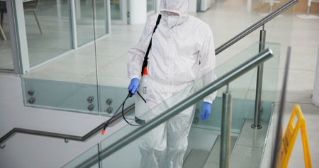Cleaner, person and spray chemicals office for fumigation, disinfect and safety suit from disease risk in building. Maintenance, liquid and pest control of healthcare, hygiene and virus cautionの写真素材