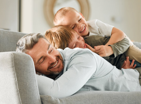 Father, kids and relax in pile in home, peace and single parent love for boys in living room. Daddy, children and stack for resting on couch for care in childhood, relationship and comfortable joyの写真素材