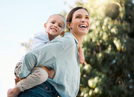 Portrait, mom and piggyback boy in outdoor for bonding activity, playful fun and childhood happiness in park. Mother, child and back hug in nature for sunshine adventure, weekend break and affection.の写真素材