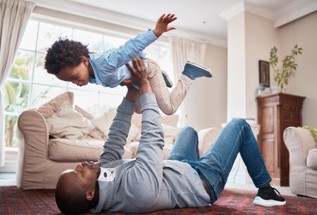 Black family, father and boy with lifting for airplane, games and playful on floor, care and love. Dad, child and son with flight, plane and balance on living room carpet with connection in homeの写真素材