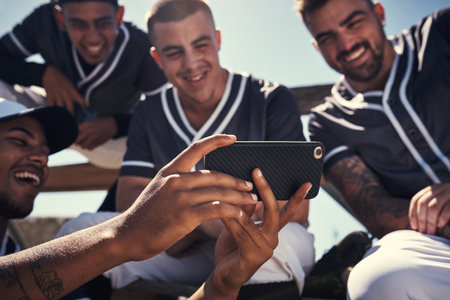 Baseball player, men and smile with smartphone for team talk with strategy, video or diversity on break at stadium. People, group and review for game, contest or training on mobile app in Los Angelesの写真素材