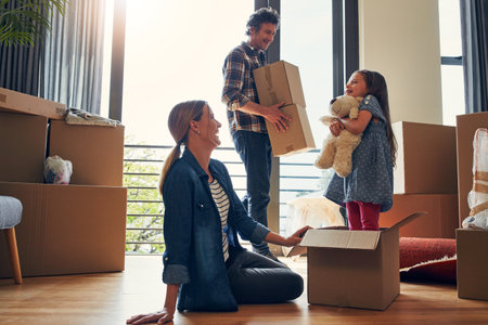 Happy, boxes and parents with child in new home bonding together for family time with teddy bear. Laugh, moving and girl kid play with mom and dad for fun and unpacking cardboard package for house.の写真素材