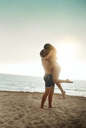 Care, lifting and couple at beach with hug on vacation, adventure or holiday for valentines day. Intimate, love or man with embrace for bonding together or woman by ocean for romantic trip on islandの写真素材