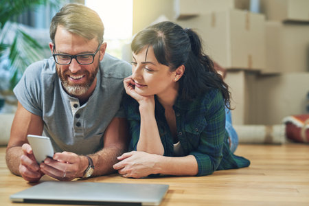 Couple, moving and happy browsing on smartphone, smile and ecommerce for apartment purchase with...