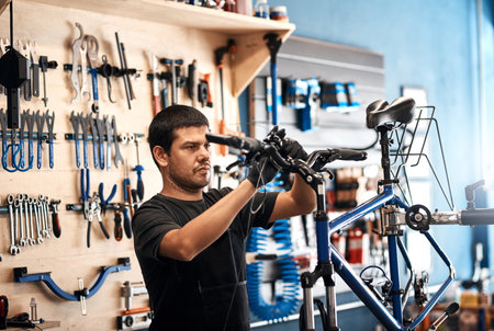 Bike repair, handlebars and maintenance with man in workshop for frame building or professional engineering. Assessment, bicycle and fixing with mechanic or technician in startup for restorationの写真素材