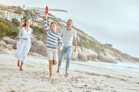 Parents, boy and plane toys at beach with running, smile or bonding with love on vacation in summer. Dad, mother and child on holiday with airplane, games or playful with family in sunshine by oceanの写真素材