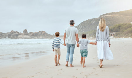 Parents, children and holding hands at beach with back, walk or bonding with love on vacation in summer. Father, mother and kids on holiday for connection, embrace or together with family in sunshineの写真素材