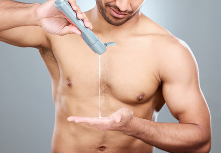 Hands, skincare and lotion with shirtless man in studio on a gray background for his grooming routine. Beauty, body and dermatology for model, moisturizing and apply with antiaging cream for skinの写真素材