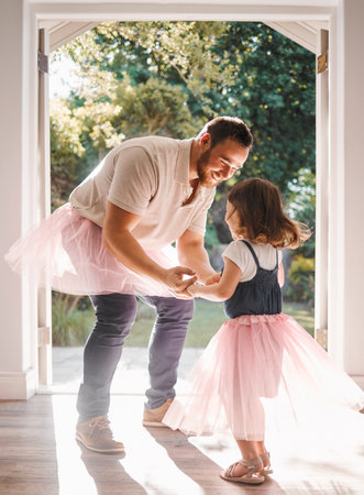 Child, dad and dance in dress in home for love, care and family bonding on fathers day. Girl, princess and happy kid with parent for playing game, holding hands and celebrate in skirt with energyの写真素材