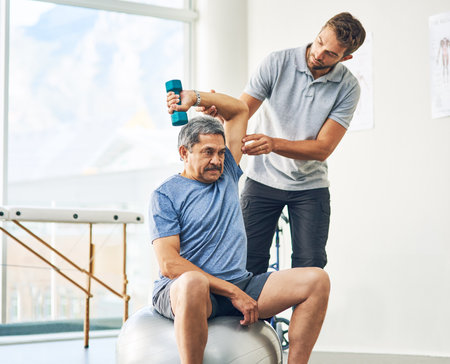 Elderly man, exercise and dumbbell with physiotherapy for rehabilitation, wellness and muscle fitness. Senior person, workout and hand weight for management of pain, arthritis and cardio healthの写真素材