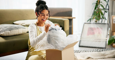 Living room, box and moving in house, woman and investment of real estate, excited and unpacking of gift. Furniture, cardboard and new home with loan, mortgage and property of apartment or relocationの写真素材