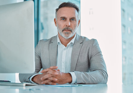 Desk, portrait and mature man at computer with confidence, trust and professional at consultancy. Advisor, project manager and serious businessman in office for online support in business developmentの写真素材