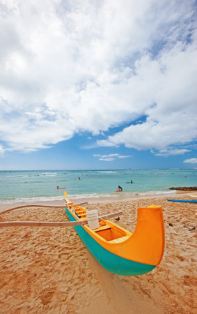 Beach, transport and boat on sand for adventure, summer vacation and blue sky with clouds. Island paradise, tropical and colorful canoe by ocean for holiday break, water travel and horizon in Hawaiiの写真素材