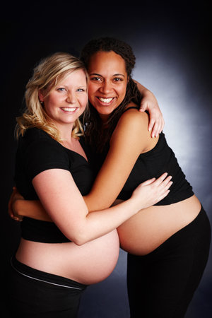 Pregnant, friends and studio or hug with stomach, bonding and woman together for diversity support. Family planning, maternity and pregnancy care, gestation and gynecology on happy black backgroundの写真素材