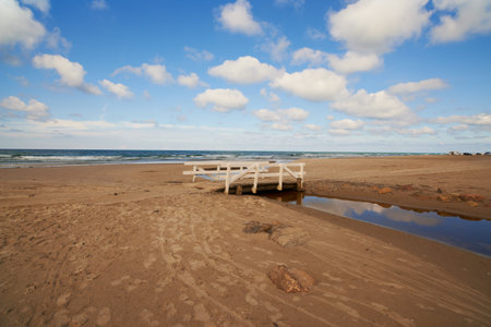 Sand, ocean and seascape with small bridge for water crossing, environment care and horizon in Denmark. Nature, landscape and sea ecosystem at river mouth, human intervention and west coast beachの写真素材
