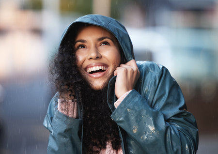 Happy woman, thinking and rain in city for winter, memory and gratitude for weather in street. Water, smile and female person with idea in town for adventure or journey, freedom and travel in Denmarkの写真素材