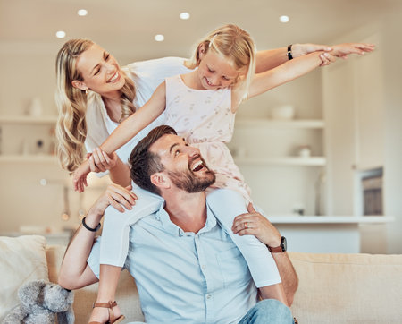 Happy, piggyback and family in living room for love, airplane game and play together on weekend. Mom, dad and girl child on sofa for happiness and laughing in home with comedy or development and funの写真素材