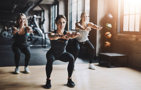 Exercise, class and people with squat in gym for muscle development, workout and challenge. Fitness,...