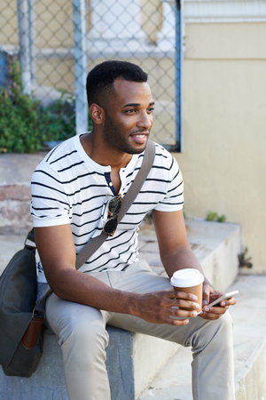 Black man, coffee and phone in city for thinking, social media and online in outdoor for insight....