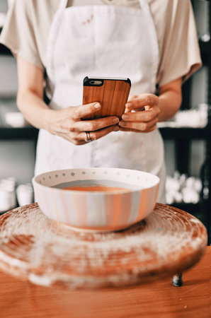 Woman, picture and phone in studio for pottery, painting and creative website with art, screen and hand. Artist, smartphone and ceramics for small business, live streaming and video as online courseの写真素材
