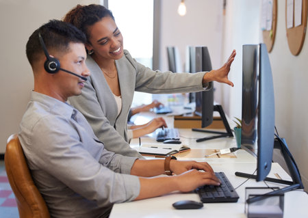 Man, mentor and call centre with headphone on computer in office as agent training, support or collaboration as customer service. People, coaching or telemarketing with client as sales consultantの写真素材