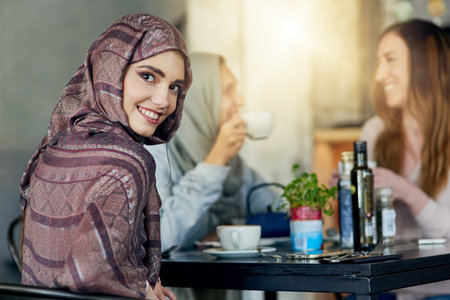 Restaurant, muslim woman and portrait with friends for food, diversity and chat with lunch in Turkey. Cafeteria, females and meal of halal friendly, coffee and nutrition for eating while bondingの写真素材