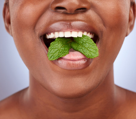 Hygiene, woman and leaf in studio with closeup for treatment, healthy teeth or fresh breath on gray...