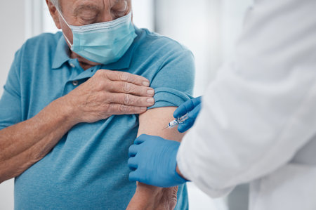 Senior man, doctor and vaccine in clinic for healthcare, wellness and prevention for virus. Retired male person, injection and medical worker with mask for protection, cure and safety in hospitalの写真素材