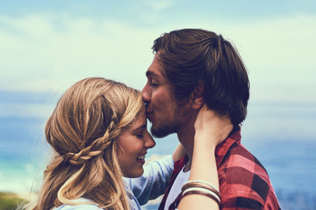 Couple, happy and forehead kiss on mountain on hike break for love with peace, care and trust in England. People, relationship and adventure on hill for holiday or vacation for fun, support and relaxの写真素材