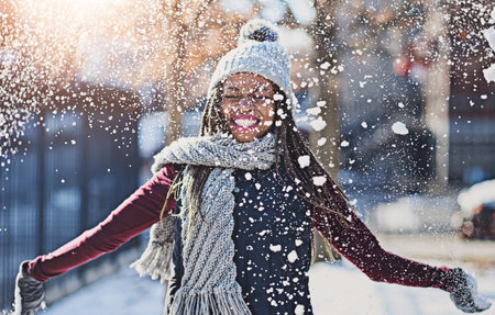 Playful, snow and black woman in city, cold and winter with fun, happiness and vacation in New York. African person, outdoor and season with girl, cheerful and weather with break, urban town and joyの写真素材