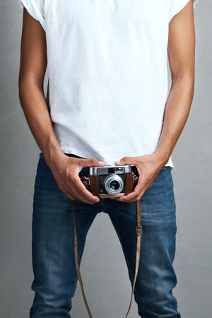 Camera, photography and hands of man in studio for digital media, photoshoot and production. Body, photographer and lens with vintage equipment for creative, art and documentation on gray backgroundの写真素材