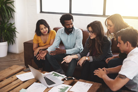 Brainstorming, people and laptop on couch in office for discussion, planning and paperwork. Engineer, team and online in creative agency for meeting and development or strategy and graph for projectの写真素材