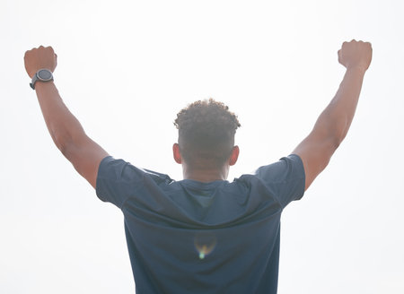 Man, success and fist pump for fitness in outdoor, strong champion and winner in training. Male person, professional athlete and back for workout achievement, sky background and competition goalsの写真素材