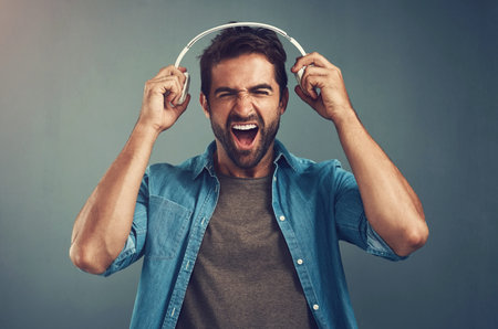 Excited, man and headphones for music in studio backdrop for edgy, cheerful on gray background. Male...
