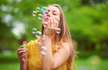 Nature, fun and woman blowing bubbles in outdoor park for happiness, holiday or summer vacation....
