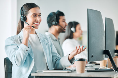 Call center, computer and woman in telemarketing office for assistance, communication or help. Desk, headset and smile with employee at work for customer service or support as virtual assistantの写真素材