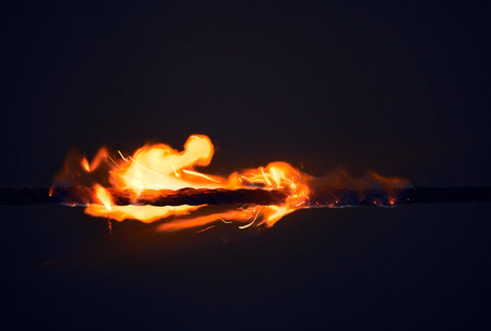 Fire, small and flame on black background in nature with heat, sparks and rope for light or energy....
