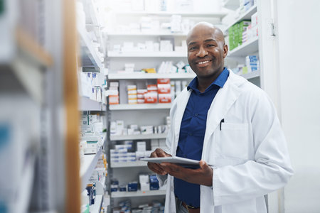 Black man, portrait and pharmacist with tablet in clinic of medicine stock, reading and check information on label. Smile, male person and digital for medical inventory, inspection and distributionの写真素材