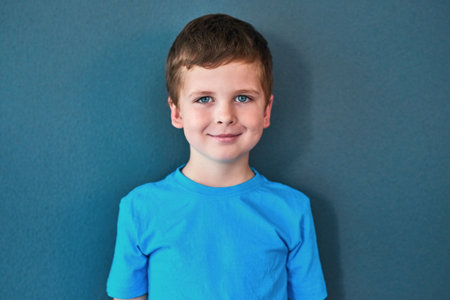Boy, child and portrait with smile in studio, happiness for education in New York City. Male student, elementary grade and cheerful for knowledge in classroom, back to school on blue backgroundの写真素材