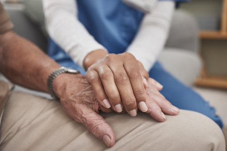 Senior care, man and nurse on sofa holding hands with support, advice or trust at nursing home...