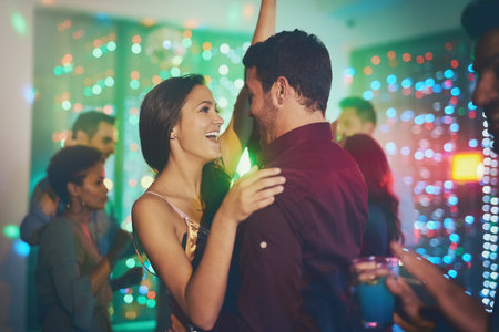 Couple, celebrate and dance in club at night on date with love in marriage or relationship. People, hug and embrace together with happiness at neon disco, party or rave at techno music festivalの写真素材