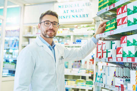 Pharmacy, pharmacist and portrait of man by shelf for wellness, medicine and medical service. Healthcare, pharmaceutical and person in dispensary for medication, supplements and prescription helpの写真素材
