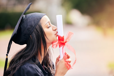 Kiss, diploma and student at graduation with certificate from college, education and achievement. Study, celebration and girl with pride for university degree, success and gratitude for scholarshipの写真素材