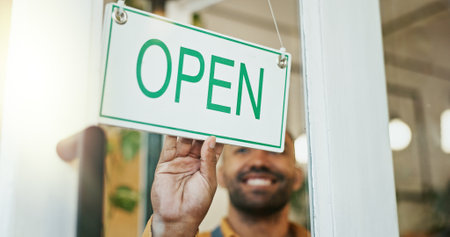 Happy man, waiter and door with open sign for welcome or small business startup at indoor coffee shop. Male person, barista or employee with smile by entrance or ready for service at cafe restaurantの写真素材