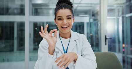 Doctor, portrait and ok results in hospital for healthcare, wellness and professional medical service. Woman, face and consulting in clinic for health, assessment and good news during internshipの写真素材