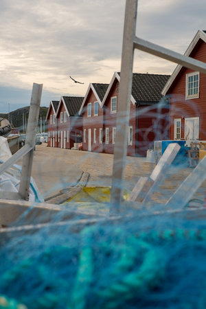 Fishing, houses and boat in port for journey, travel and business in village or small town. Buildings, sky or clouds and close up of net for industry, hospitality and shipping or location by oceanの写真素材