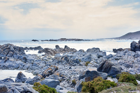 Coastline, sea and waves landscape with horizon and rocks for peace, travel destination and holiday location. Beach, cloudy sky and ocean water for vacation environment, skyline and scenery in natureの写真素材