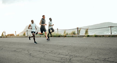 Athletic, men and team in challenge for marathon, exercise and sport in outdoor for fitness or wellness. Male people, runners and nature for practice, race or recreation as athlete in training in USAの写真素材